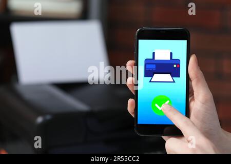 Man using printer management application on mobile phone indoors, closeup and space for text Stock Photo