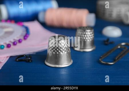Silver thimble on blue wooden table, space for text. Sewing accessories Stock Photo