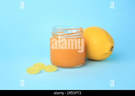 Cough drops, fresh lemon and honey on light blue background Stock Photo