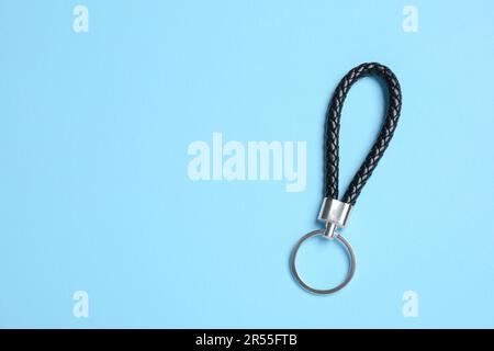 Black leather keychain on light blue background, top view. Space for text Stock Photo