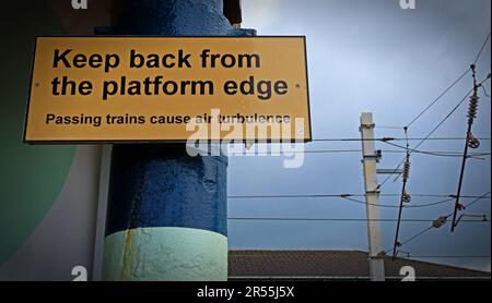 Railway safety sign warning passengers to keep back from the platform edge due to air turbulence from passing trains, photographed at a UK station Stock Photo