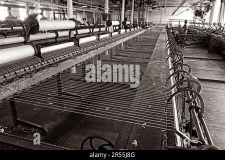 Cotton ring spinning frame inside a Lancashire spinning mill, showing rows of spindles twisting and winding yarn during industrial textile production. Stock Photo