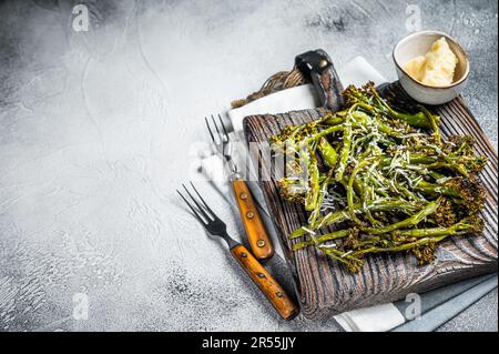 Baked Broccolini cabbage Sprouts with parmesan cheese on wooden board. White background. Top view. Copy space. Stock Photo