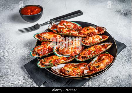 Large green mussels cooked in tomato sauce with garlic, parsley and lemon. White background. Top view. Stock Photo