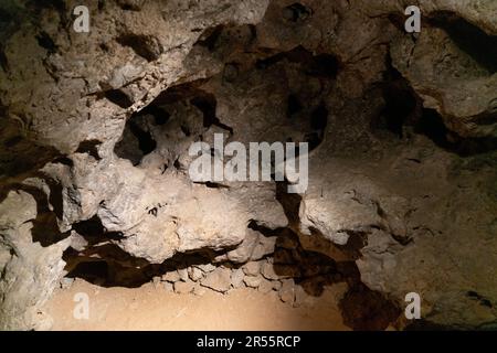 Rough, hollowed brown rock with sharp edges and small cavities fills the frame, lit from the lower left in Carlsbad Caverns National Park, New Mexico. Stock Photo
