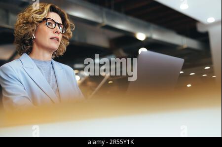 business woman having an online meeting in a coworking space. Professional business woman having a conference call with a laptop. Female professional Stock Photo