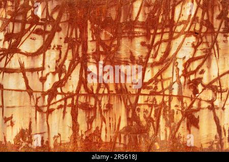 A red brown abstraction of scratched rusty lines and textures on an old weathered metal industrial surface. Random impact marks on a steel wall. Looks Stock Photo