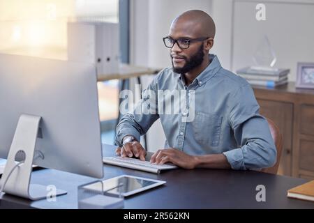 Programmer, computer and black man typing for software, coding or email in office. IT, desktop and African professional working on cyber security Stock Photo