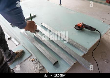 Man assembles profile metal frame for plasterboard ceilings Stock Photo