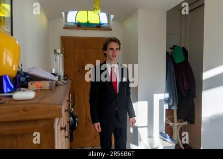 student teenager in black suit is about to leave from home to pass an secondary school-leaving exam - series Stock Photo