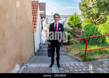 student teenager in black suit is about to leave from home to pass an secondary school-leaving exam - series Stock Photo