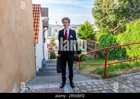 student teenager in black suit is about to leave from home to pass an secondary school-leaving exam - series Stock Photo