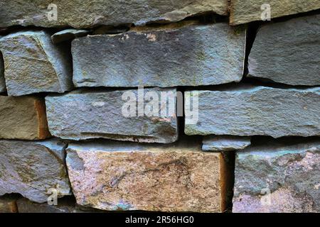 An old dry stone slate garden wall. The stones are stacked. The color is mainly grey Stock Photo