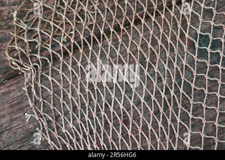 Part of a knotted fishing net on a dark wooden background Stock Photo