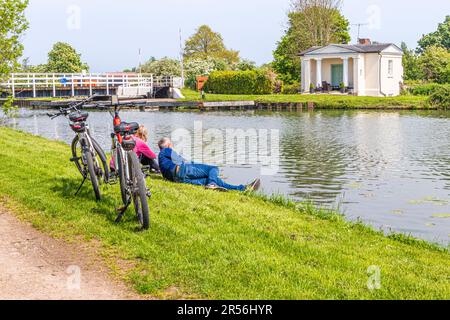 Cycling couple resting on the Towpath Trail beside the Gloucester and Sharpness Canal at Splatt Bridge at the Severnside village of Frampton on Severn Stock Photo