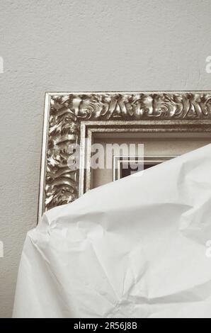 partially unwrapped painting leaning against a wall Stock Photo