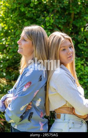 Mother and teen daughter back to back, fighting Stock Photo