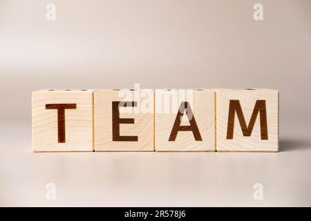 The word TEAM on wooden cubes on a beige neutral studio background. Copy Space. Written. Text words matter. Teamwork, Ideas for business corporation c Stock Photo
