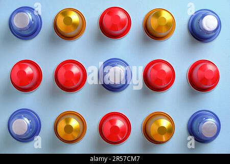 Multi-coloured coffee pods in a grid against a plain background. Top down view. Stock Photo