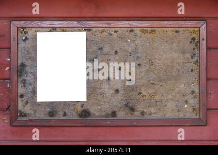 Old bulletin board with an empty white note on red wooden wall. Stock Photo