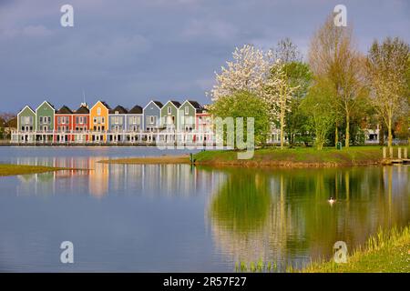 Houten, The Netherlands - April 25 2023. Trees and colourful wooden lakeside houses reflected in the water of lake De Rietplas. Stock Photo