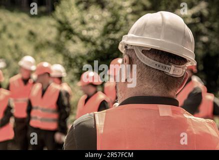 Worker group wearing vest, safety. Building concept. Architector, engineers on constructing site. Builder man. Helmet builder. Many construction Stock Photo
