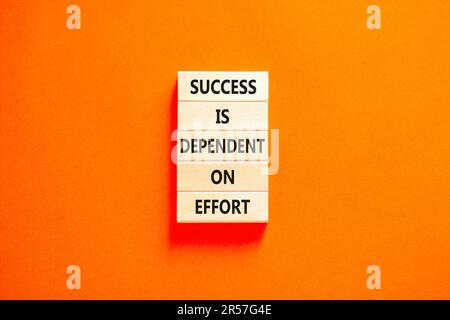 Success and effort symbol. Concept words Success is dependent on effort on wooden block. Beautiful orange table orange background. Business success an Stock Photo