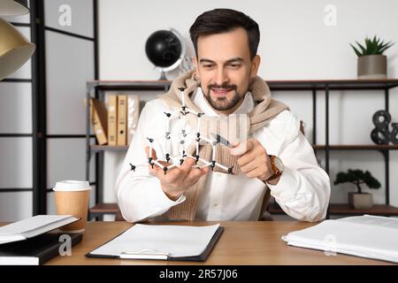 Male tutor with molecular model giving online Physics lesson at home Stock Photo