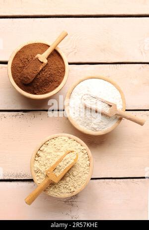 Wooden bowls with different types of flour and cacao on light wooden background Stock Photo