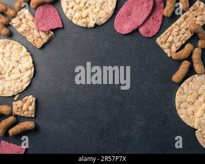 Organic crackers from lentils, beet, nuts and corn as a frame on a stone background, space for your text Stock Photo