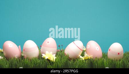 Pink Easter eggs in a row on grass with flowers, holiday or spring time concept Stock Photo
