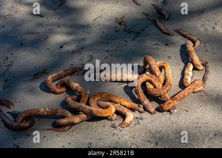 Rusty old chain half buried in the sand Stock Photo