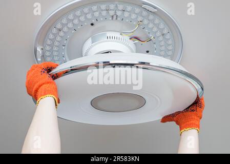 An electrician installs a chandelier on the ceiling. Stock Photo