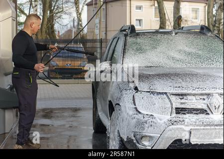 Kaliningrad, Russia, March 1, 2020. A man washes his car at a touchless car wash. Washing his brown Renault car. The SUV at the car wash. Stock Photo