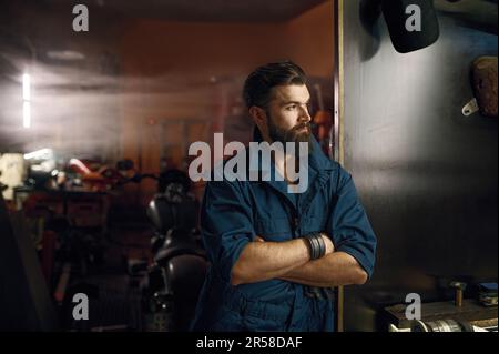 Pensive repairman searching idea while looking at window of motorcycle workshop Stock Photo