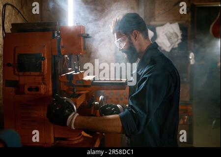 Repairman working on milling machine in smoky space of workshop Stock Photo