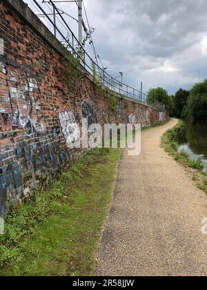 Walking along the Bridgewater Canal in Manchester with urban graffiti brick wall Stock Photo