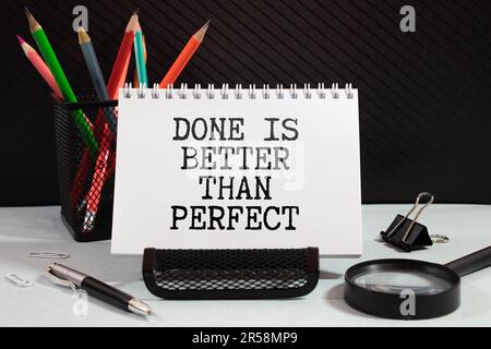 The phrase Done is Better Than Perfect on a paper note pinned to a notice board. In the interest of productivity it is sometimes better to get things Stock Photo
