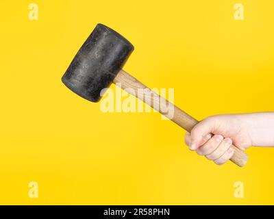 Hand with big hammer, yellow background. no face. Concept, studio. Stock Photo