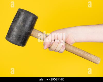 Hand with big hammer, yellow background. no face. Concept, studio. Stock Photo