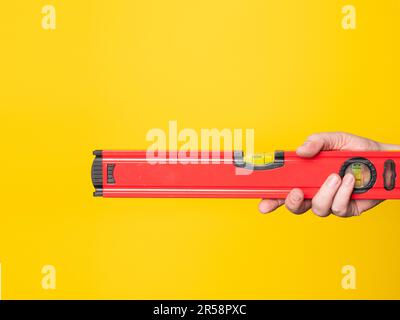 Hand holding a level. Yellow background, no face. Stock Photo