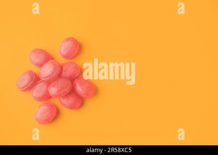 Many pink cough drops on orange background, flat lay. Space for text Stock Photo