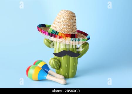 Colorful maracas, toy cactus with sombrero hat and mustache on light blue background. Musical instrument Stock Photo