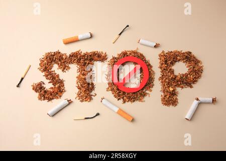 Flat lay composition with word Stop made of dry tobacco and prohibition sign on beige background. Quitting smoking concept Stock Photo