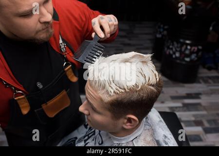 Barber's hands spray the little boy's hair with a spray gun. Stock