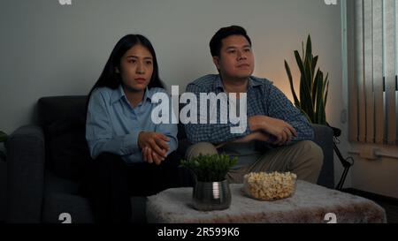 Asian couples watch movies on TV on weekends at night. Stock Photo