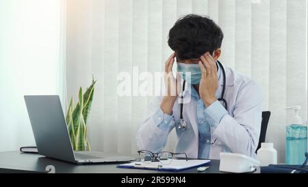 Asian young man doctor being exhausted and burnout in the office room. Stock Photo