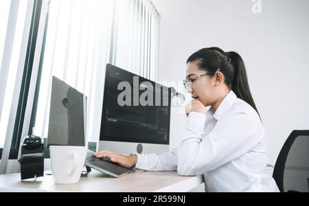 Asian female software developer is worried about analyzing code-based systems at his office. Stock Photo