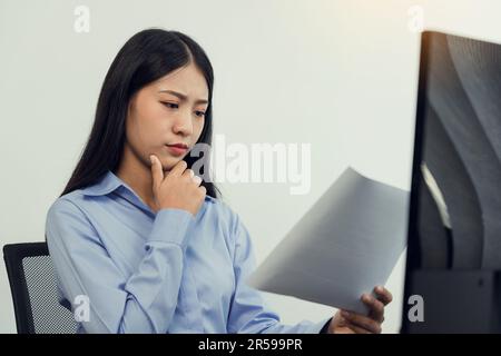 Concentrated asian woman brainstorming while coding data on desktop PC while working on computer codes in the office. Stock Photo