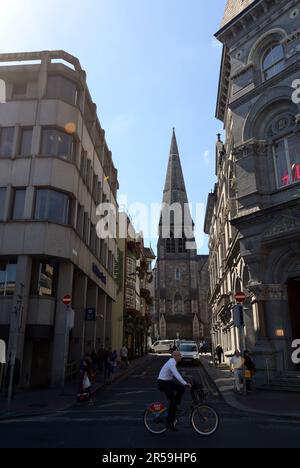 An Irish man riding his bicycle on Dame street with the St. Andrew's Church in the background. Dublin, Ireland. Stock Photo